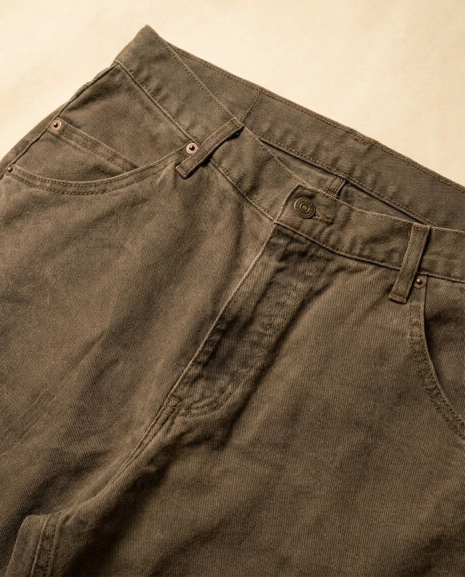 Close-up of Mica stretch denim showing the specialty wash, gold leaf button, YKK zipper fly and front pocket stitching.